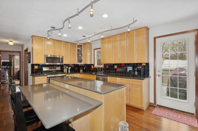 kitchen featuring stainless steel appliances, a center island, light brown cabinets, and decorative backsplash