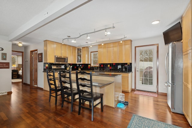 kitchen featuring tasteful backsplash, appliances with stainless steel finishes, a breakfast bar, and a wealth of natural light