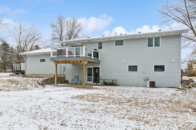 snow covered property with central AC unit and a deck