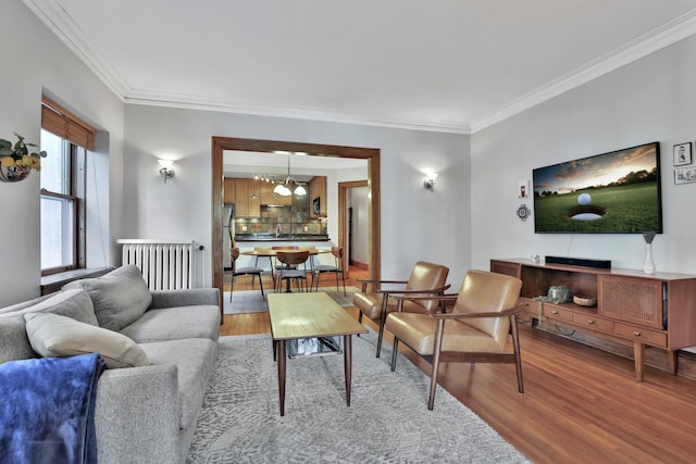 living room featuring hardwood / wood-style flooring, ornamental molding, and radiator heating unit