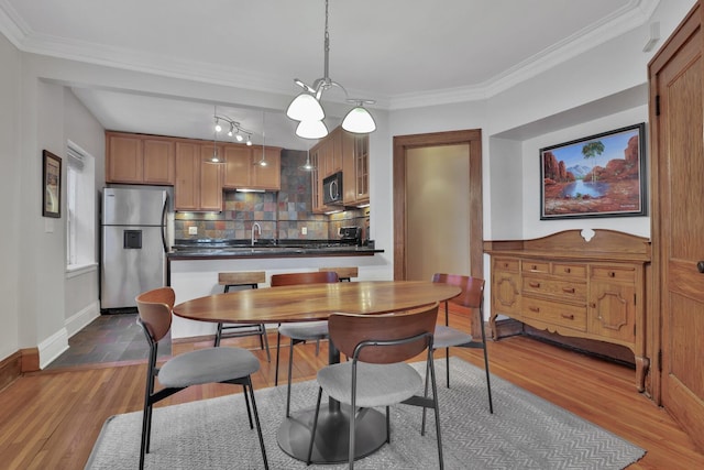 dining space with crown molding, wood finished floors, and baseboards