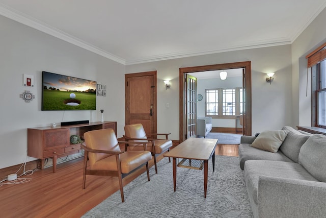 living room featuring crown molding, baseboards, and wood finished floors