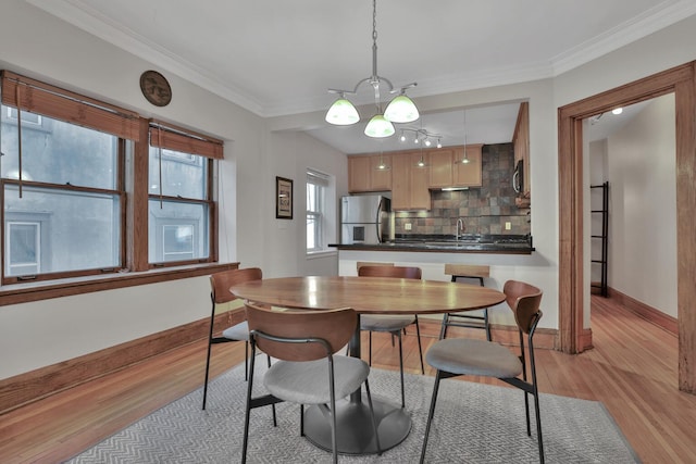 dining room with baseboards, light wood finished floors, and ornamental molding