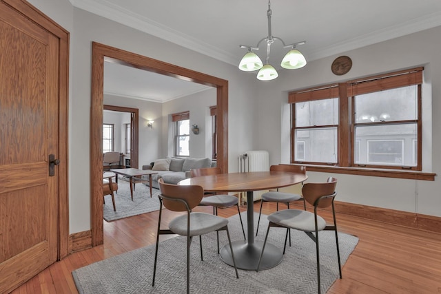 dining space with light wood-type flooring, radiator heating unit, crown molding, baseboards, and a chandelier