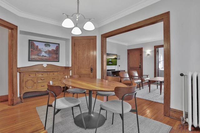 dining area featuring radiator, baseboards, ornamental molding, light wood-style flooring, and a notable chandelier