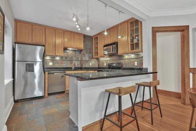 kitchen featuring crown molding, a kitchen breakfast bar, tasteful backsplash, and stainless steel appliances