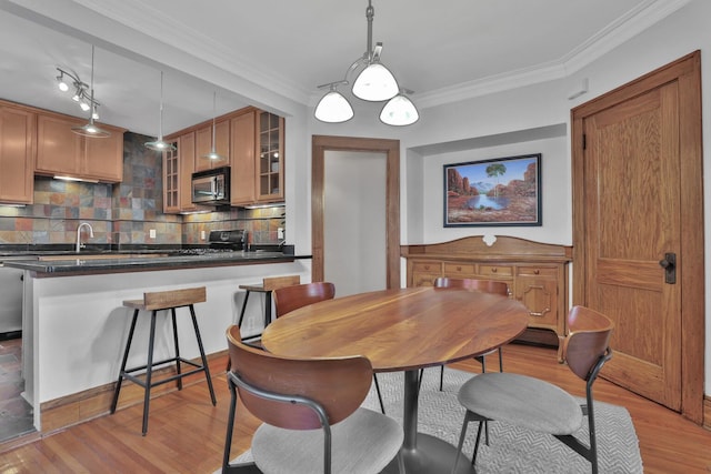 dining space with light wood-type flooring and ornamental molding