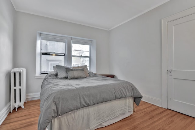 bedroom with radiator heating unit, wood finished floors, and baseboards