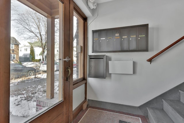 doorway to outside featuring mail area, stairway, and baseboards