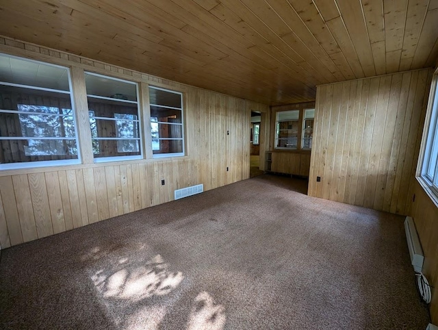 spare room featuring carpet flooring, wood walls, and wooden ceiling