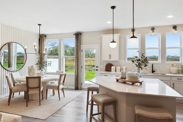 kitchen with decorative light fixtures, backsplash, white cabinetry, and a kitchen island