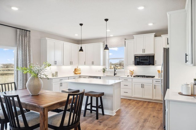 kitchen featuring black microwave, tasteful backsplash, white cabinetry, and light wood-style floors