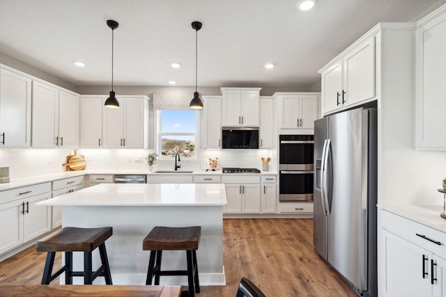 kitchen with stainless steel appliances, white cabinets, a sink, and a kitchen breakfast bar