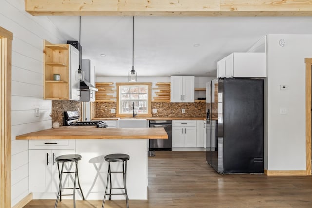 kitchen featuring a breakfast bar, stainless steel appliances, white cabinets, wood counters, and beamed ceiling