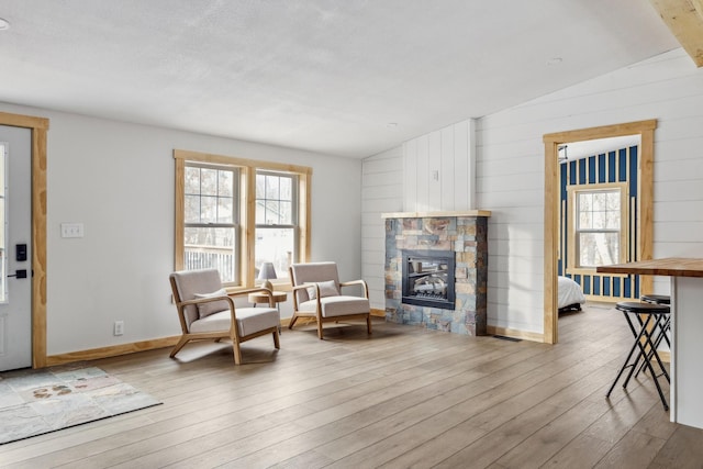 living area featuring lofted ceiling, a fireplace, and light hardwood / wood-style flooring