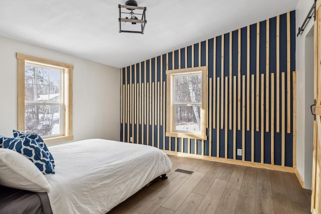 bedroom featuring wood-type flooring and a barn door