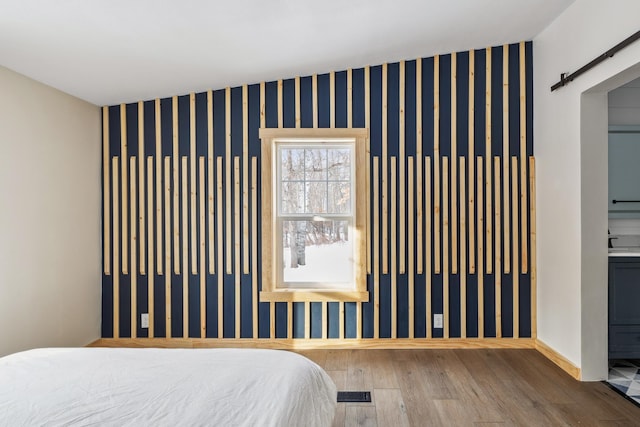 bedroom with hardwood / wood-style floors, a barn door, and ensuite bathroom