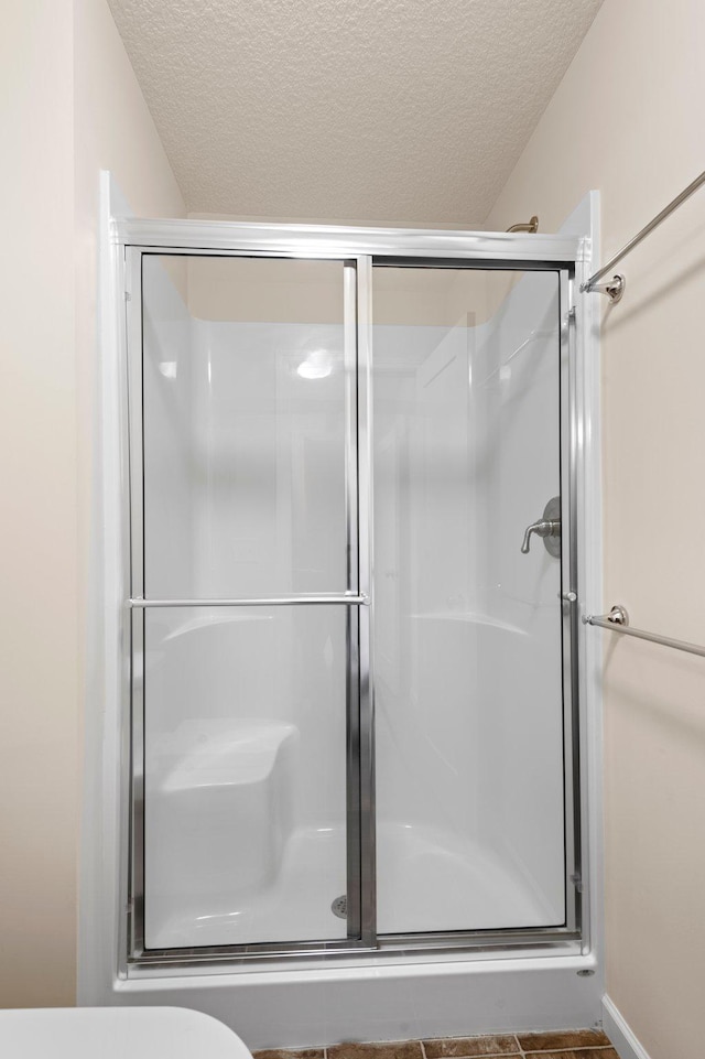 bathroom with a shower with door and a textured ceiling