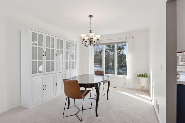 dining room with light colored carpet and a chandelier