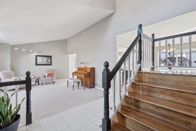 stairway featuring a notable chandelier, carpet floors, and high vaulted ceiling