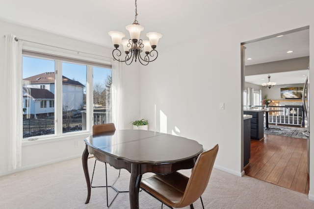 carpeted dining room featuring a healthy amount of sunlight and a notable chandelier