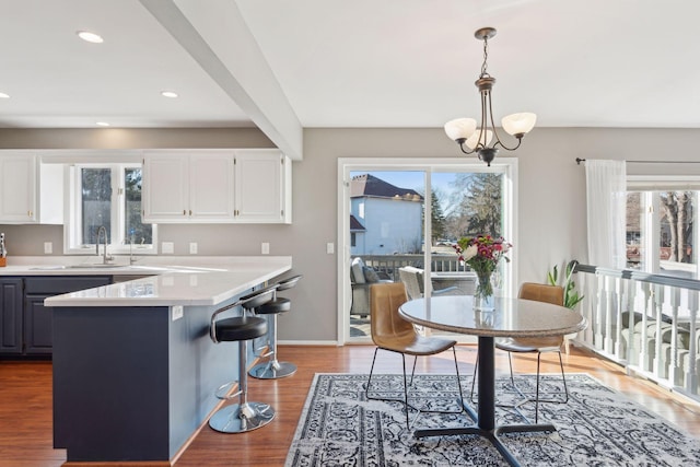 kitchen with pendant lighting, wood-type flooring, a center island, and white cabinets