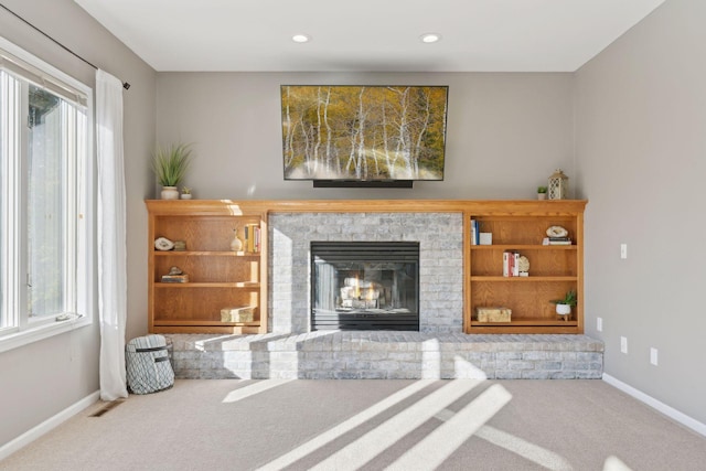 living room featuring a brick fireplace, plenty of natural light, and carpet