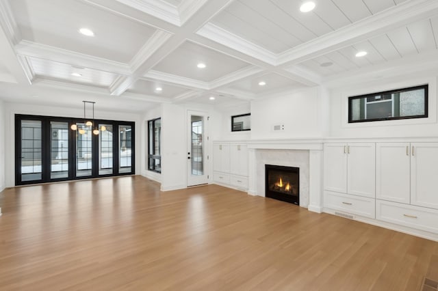 unfurnished living room featuring an inviting chandelier, coffered ceiling, ornamental molding, beam ceiling, and light hardwood / wood-style flooring