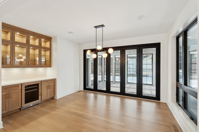 unfurnished dining area with a wealth of natural light, beverage cooler, and light hardwood / wood-style flooring