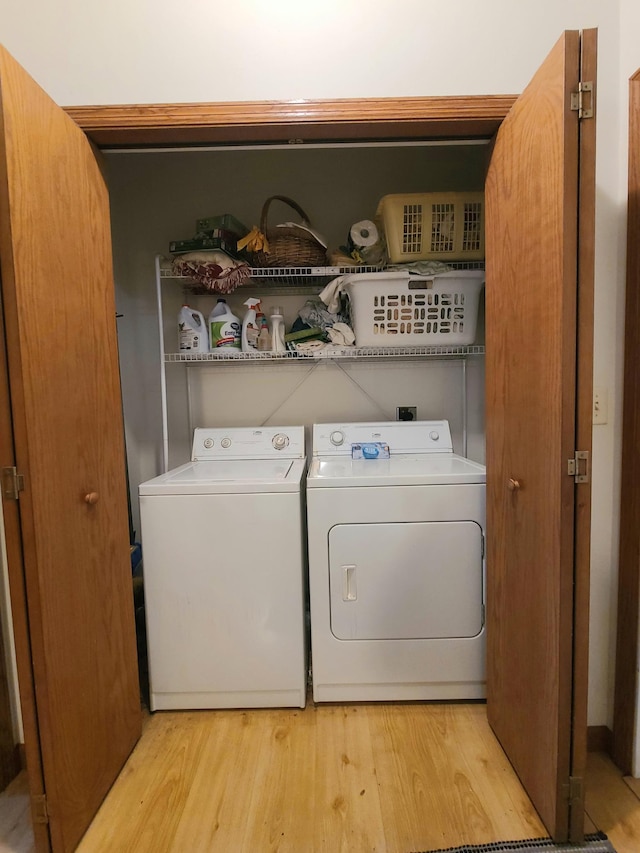 laundry area with light wood-type flooring and washing machine and clothes dryer