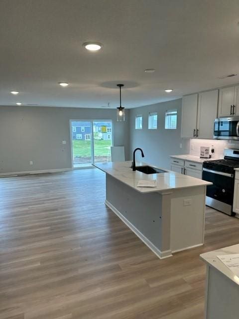 kitchen featuring appliances with stainless steel finishes, white cabinetry, hanging light fixtures, and sink