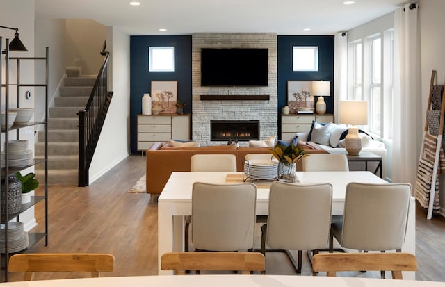 living room featuring baseboards, light wood-style flooring, stairs, a fireplace, and recessed lighting