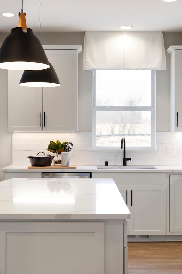 kitchen with light countertops, tasteful backsplash, a sink, and decorative light fixtures