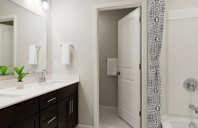 bathroom with double vanity, baseboards, a sink, and shower / bathing tub combination