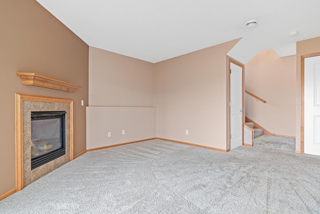 unfurnished living room featuring light carpet, a fireplace, baseboards, and stairs