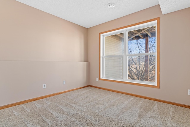 spare room featuring carpet, a textured ceiling, and baseboards