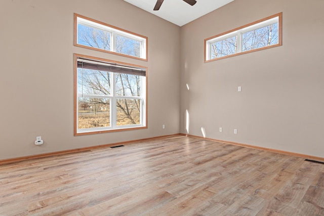 empty room with light wood-type flooring, ceiling fan, and a high ceiling