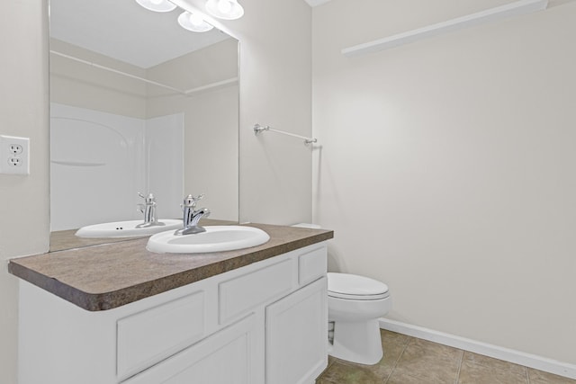 bathroom featuring toilet, tile patterned floors, baseboards, and vanity