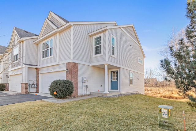 view of front of home with an attached garage, aphalt driveway, a front yard, and brick siding