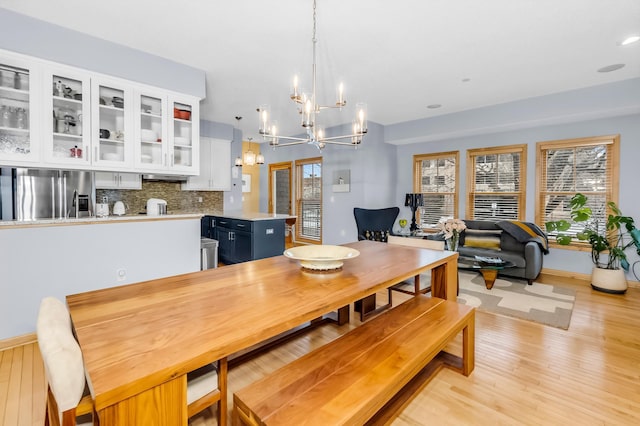 dining room with light wood-type flooring and an inviting chandelier