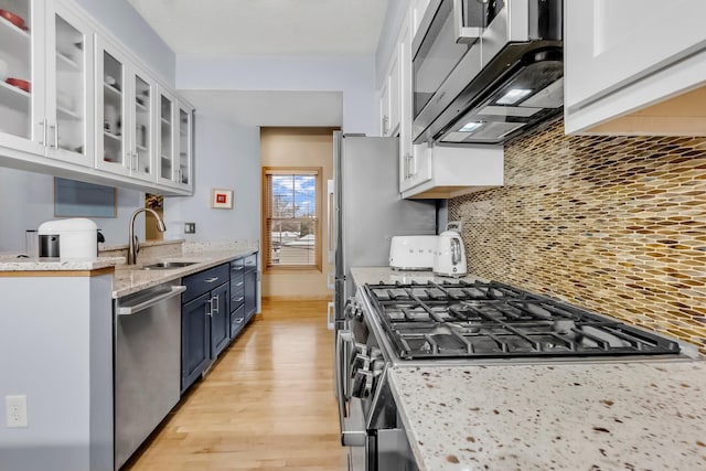 kitchen featuring appliances with stainless steel finishes, sink, white cabinets, decorative backsplash, and blue cabinetry