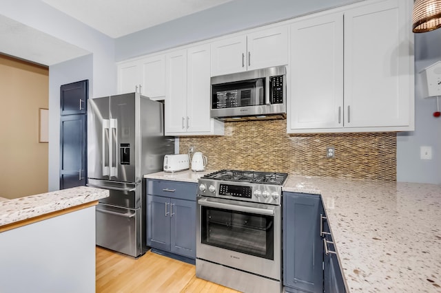 kitchen with light hardwood / wood-style flooring, appliances with stainless steel finishes, white cabinets, blue cabinets, and decorative backsplash