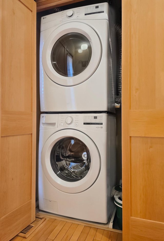 laundry room featuring stacked washer / dryer and light wood-type flooring