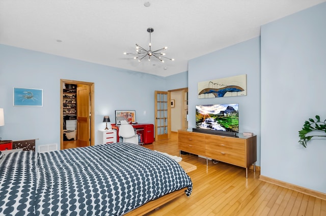 bedroom featuring hardwood / wood-style flooring, a spacious closet, and an inviting chandelier