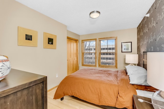 bedroom featuring light hardwood / wood-style floors, a closet, and a textured ceiling