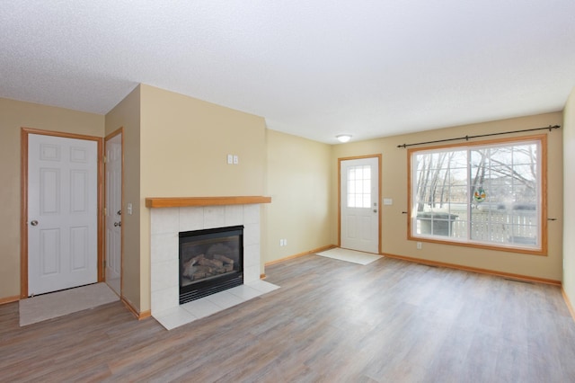 unfurnished living room featuring light hardwood / wood-style floors and a tile fireplace