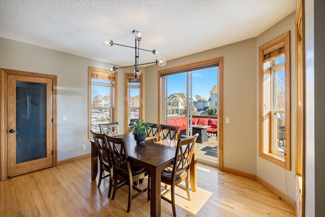 dining room featuring light wood-style floors, baseboards, and a textured ceiling