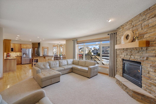 living room featuring a textured ceiling, a fireplace, light colored carpet, and recessed lighting