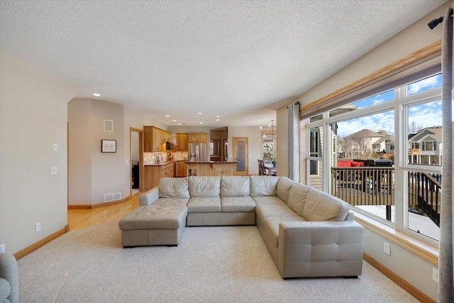 living area with baseboards, visible vents, and a textured ceiling