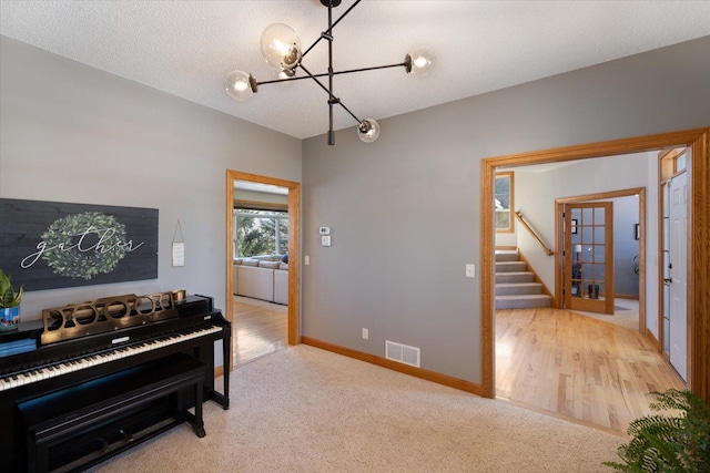 interior space with a textured ceiling, carpet flooring, visible vents, baseboards, and stairs